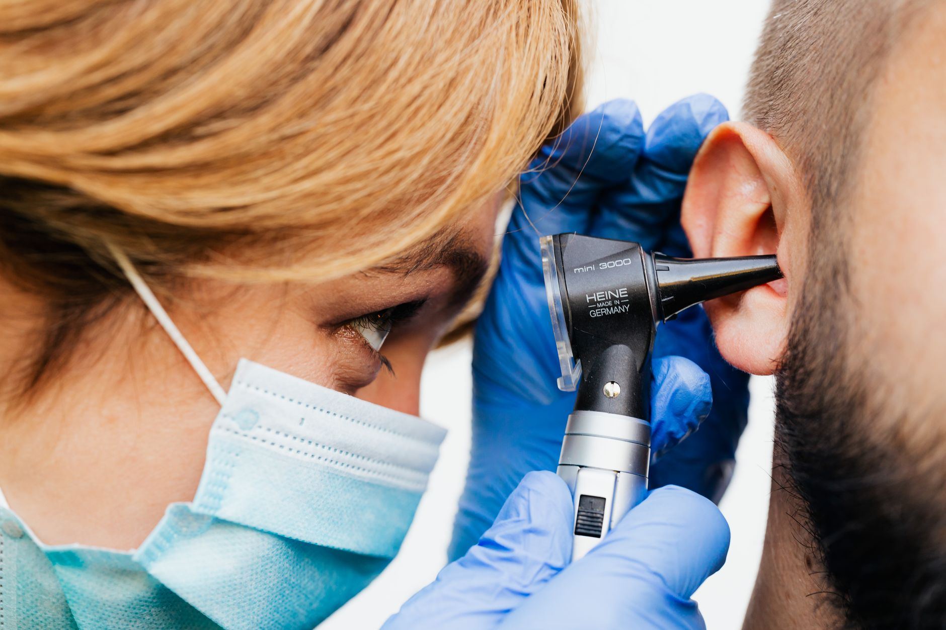 Close-up of a doctor performing an ear examination with an otoscope.